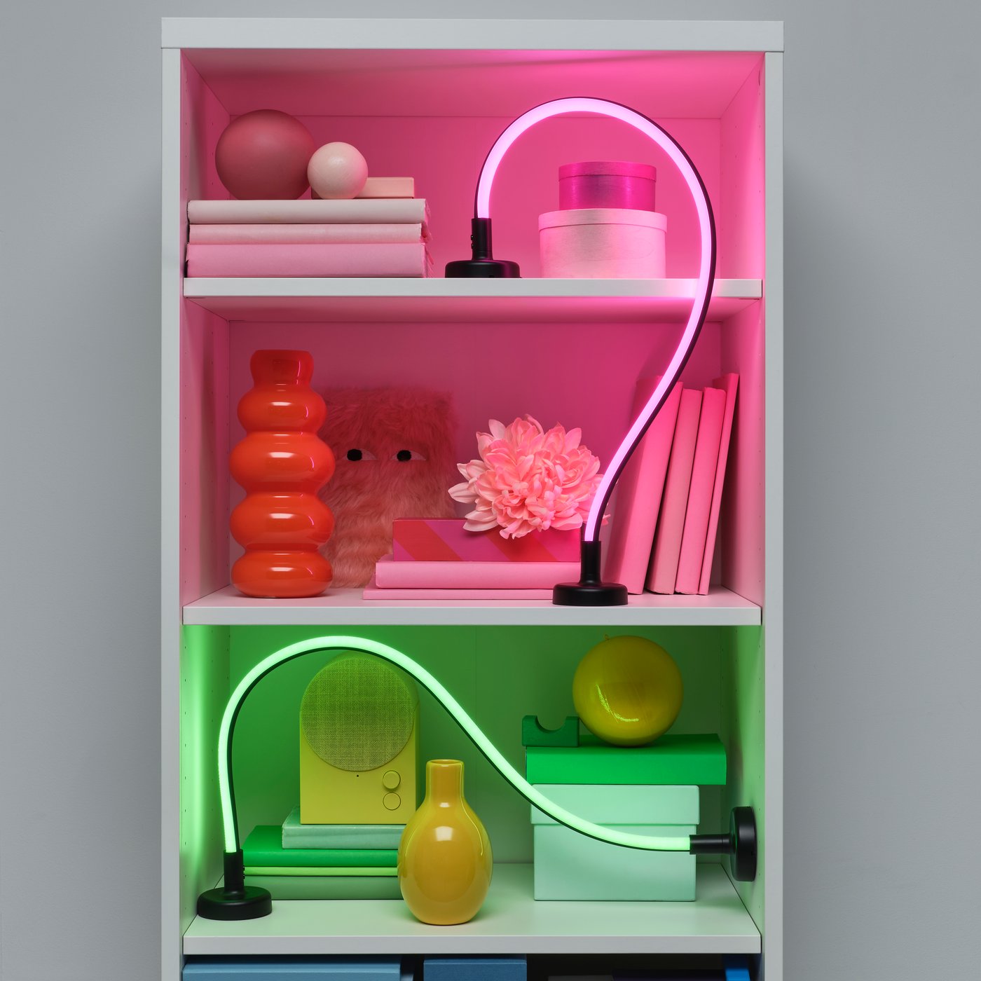Iluminación decorativa LED SMÅSNÖRE atenuable y de color ajustable colocada en un estante. 