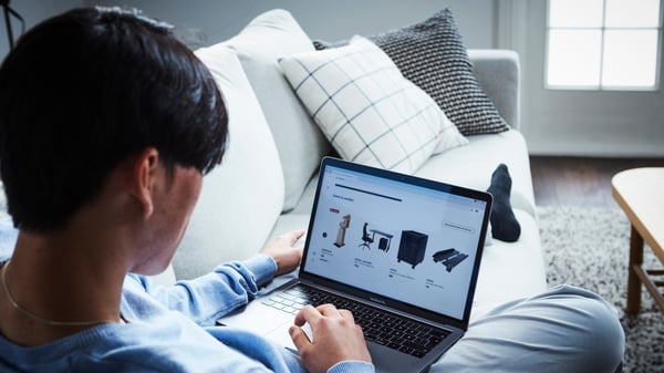 Man sitting at a sofa and searching for IKEA products on a laptop.