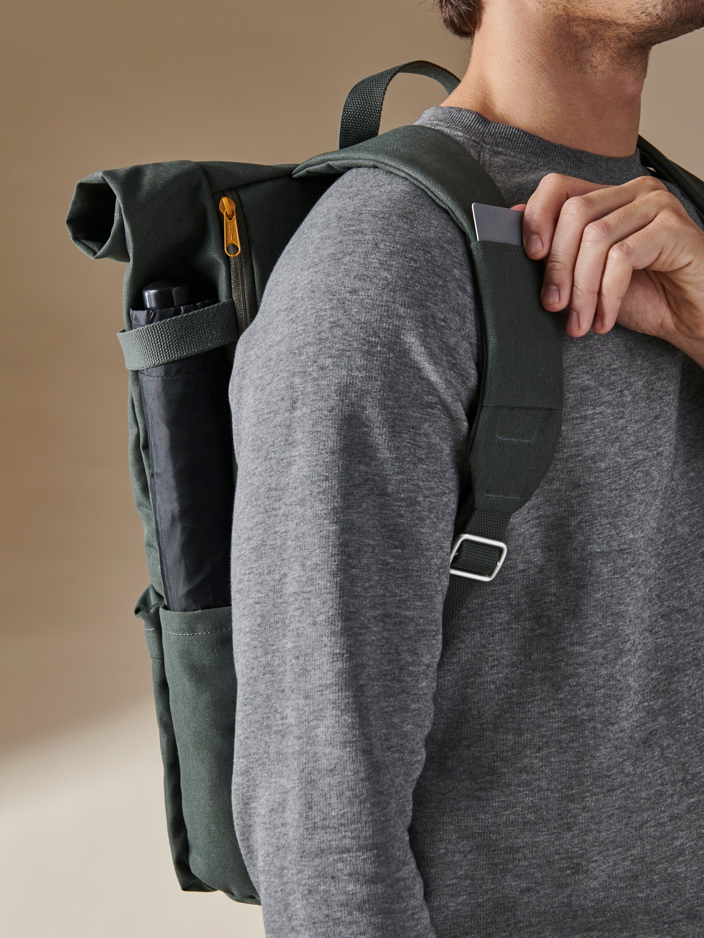 Homme portant un sac à dos vert DRÖMSÄCK, retirant une carte de son logement dans l’une des bretelles.