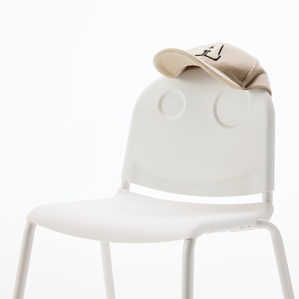 Close-up of a white VILDGÅS junior chair. It has a ballcap on top and the pattern on the back looks like a smiling face.