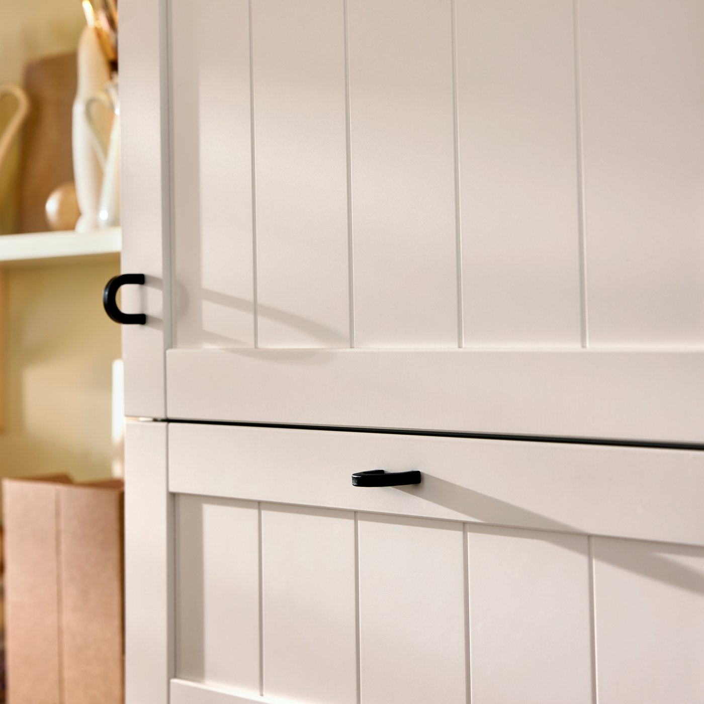 A close-up of white BESTÅ storage with a PIPMAKARE door and a PIPMAKARE drawer front, both with a BORGHAMN handle.