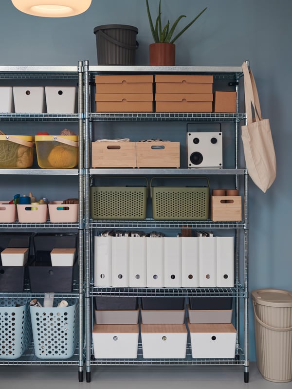 Two OMAR shelves, placed next to each other, are neatly stacked with different boxes in a room with blue walls.
