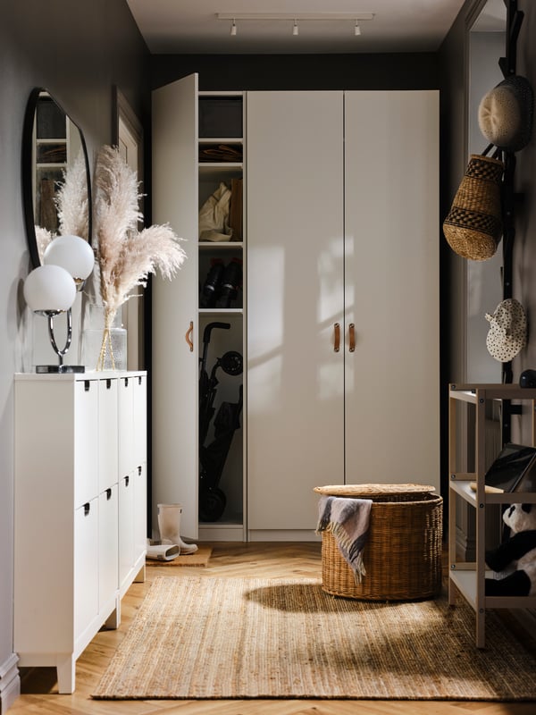 A PAX/FORSAND wardrobe at the end of a hallway with a LOHALS rug on the floor, with one door open showing outdoor equipment.