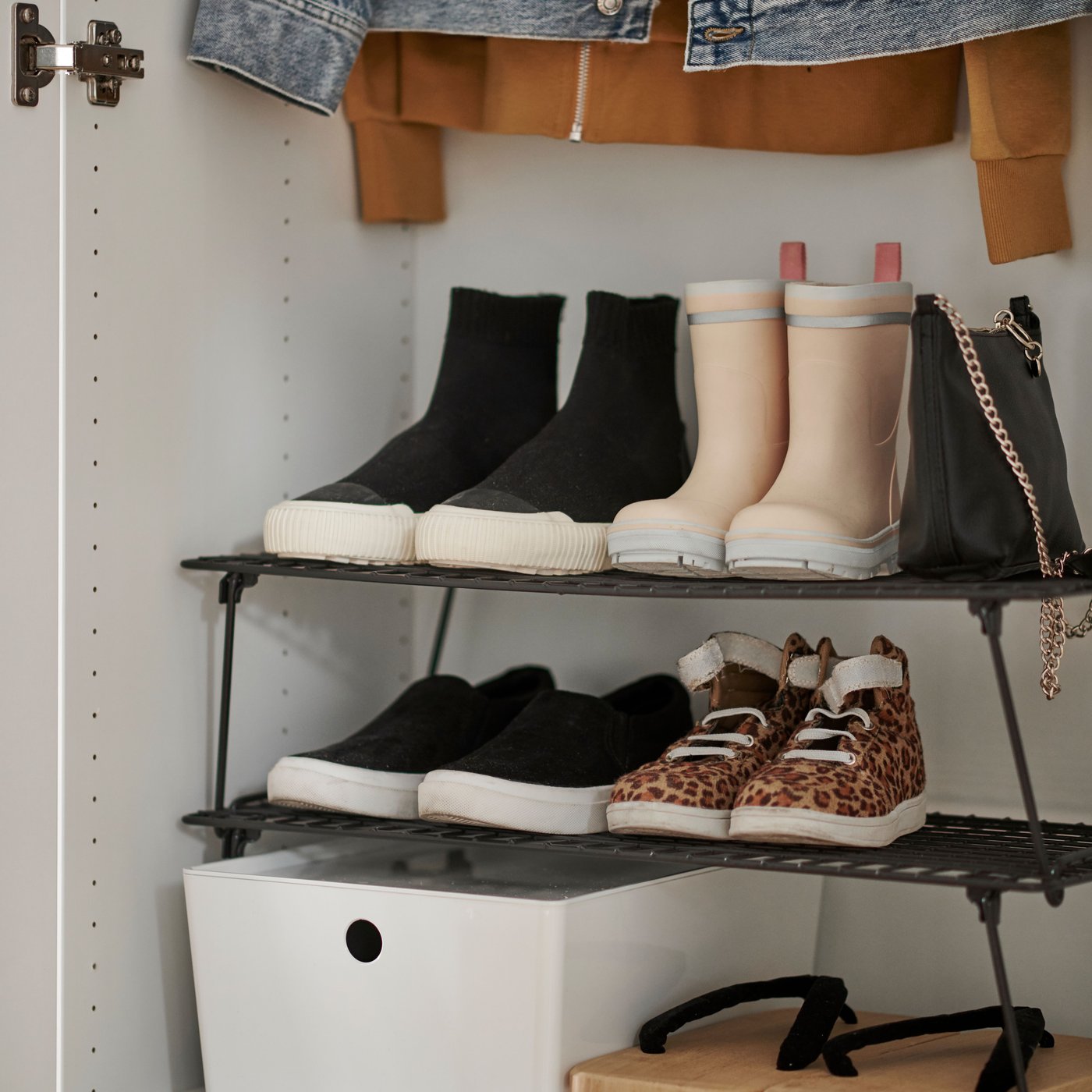 Two grey GREJIG shoe racks stacked on top of each other in a wardrobe holding shoes, adult and children’s boots and a bag.