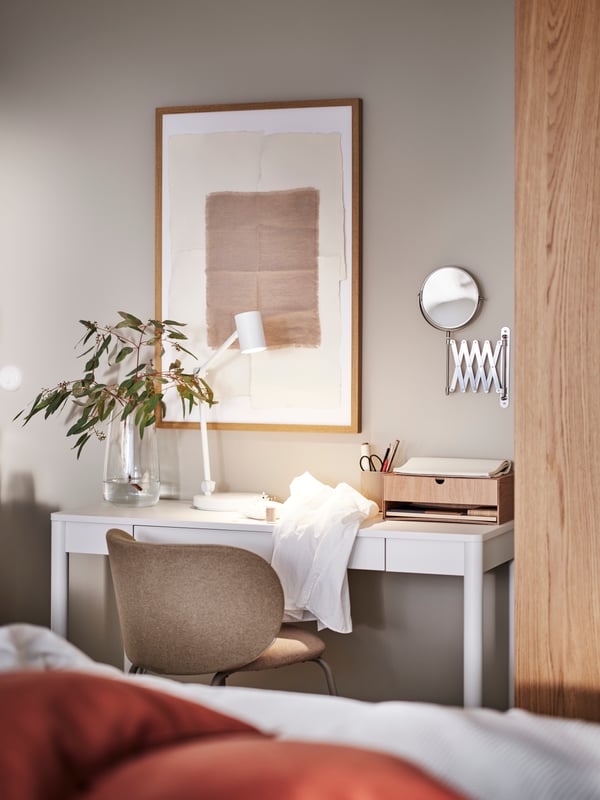 An off-white TONSTAD desk with various items on top by a PAX/TONSTAD wardrobe and with a dark beige KRYLBO chair in front.
