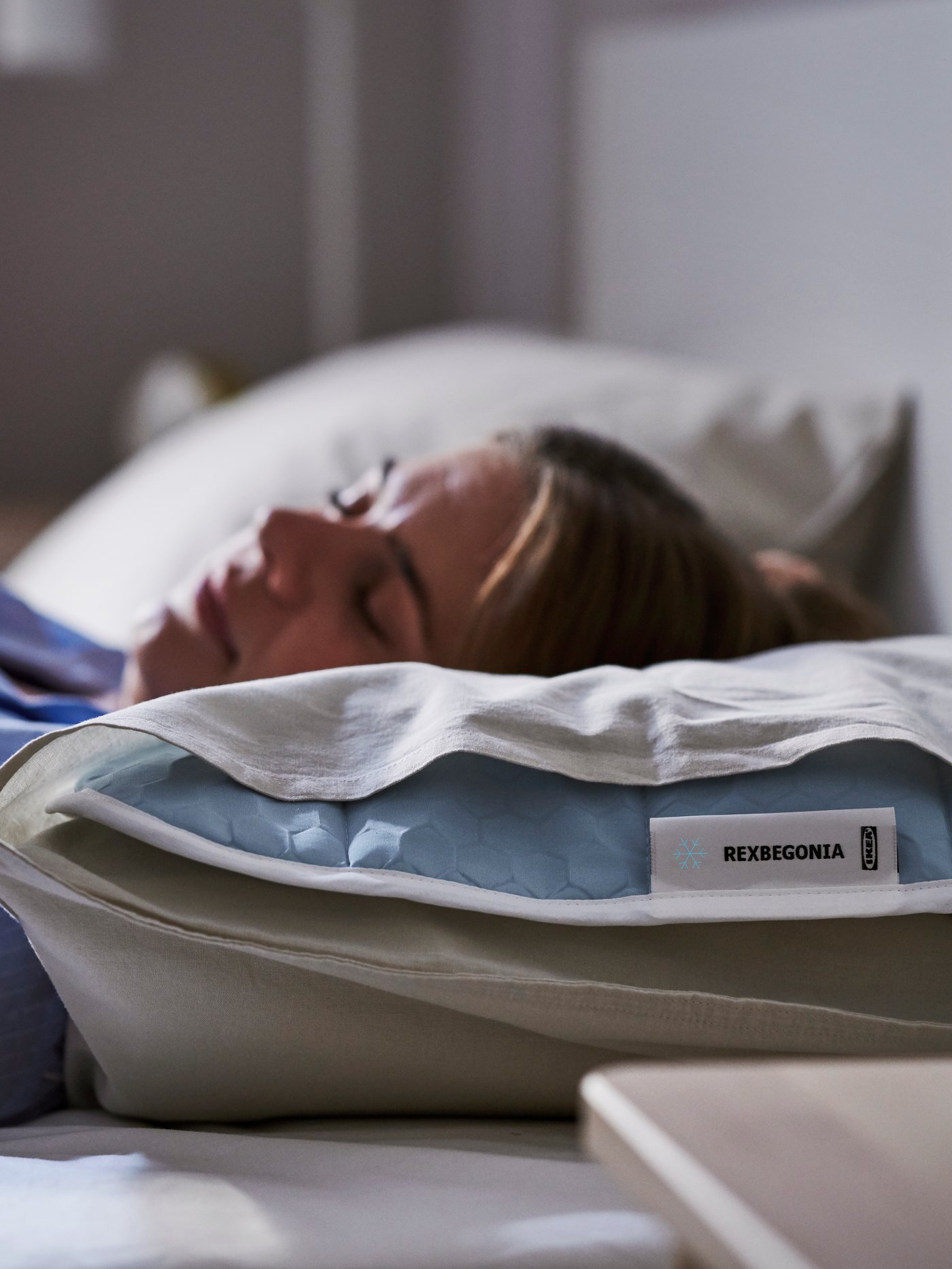 Close-up of woman sleeping with her head resting on a pillow with REXBEGONIA cooling pad tucked inside the pillowcase.