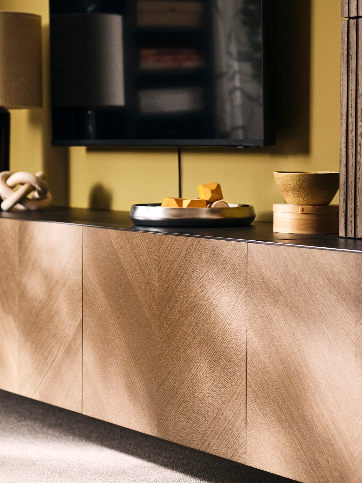 BESTÅ media storage combination with closed cabinets and decorative items beneath a TV in a living room.