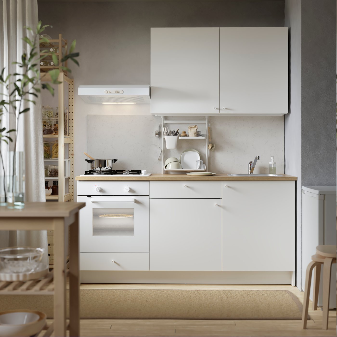 A LAGAN freestanding fridge/freezer in white in the corner of a kitchen with a mat on the floor and a paper bag of food.