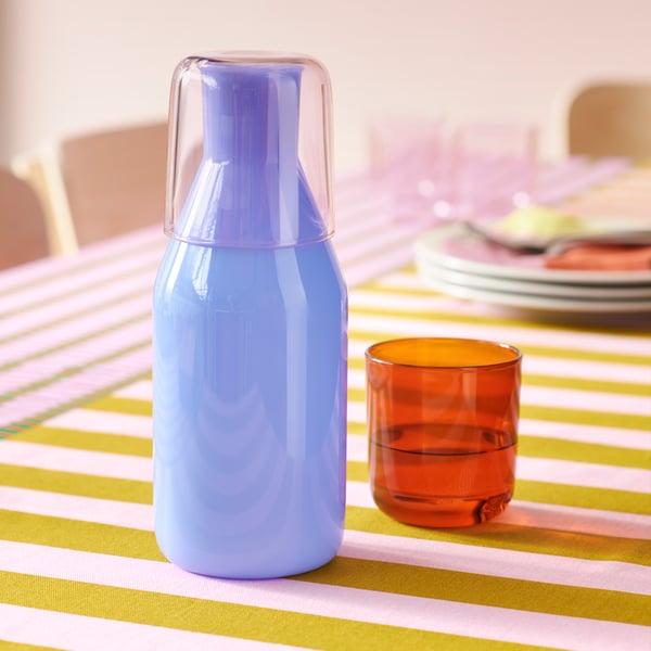 En lila karaff står på ett bord med en rutig duk - passande för dopamine decor stilen.