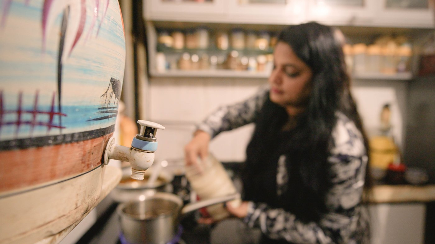 A woman standing in the background of a pot of different patterns.