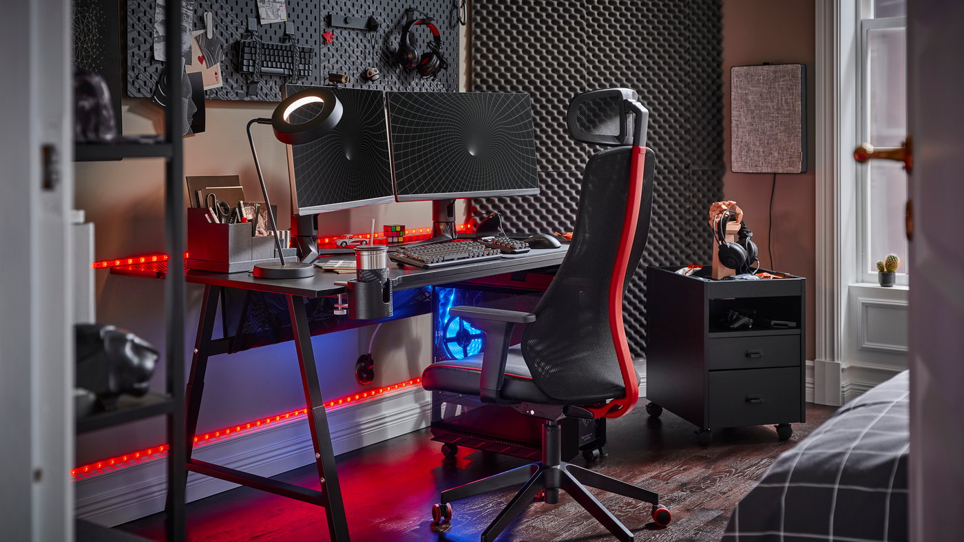 A black UTESPELARE gaming desk with two screens, a black gaming chair, a black drawer unit and various gaming accessories.