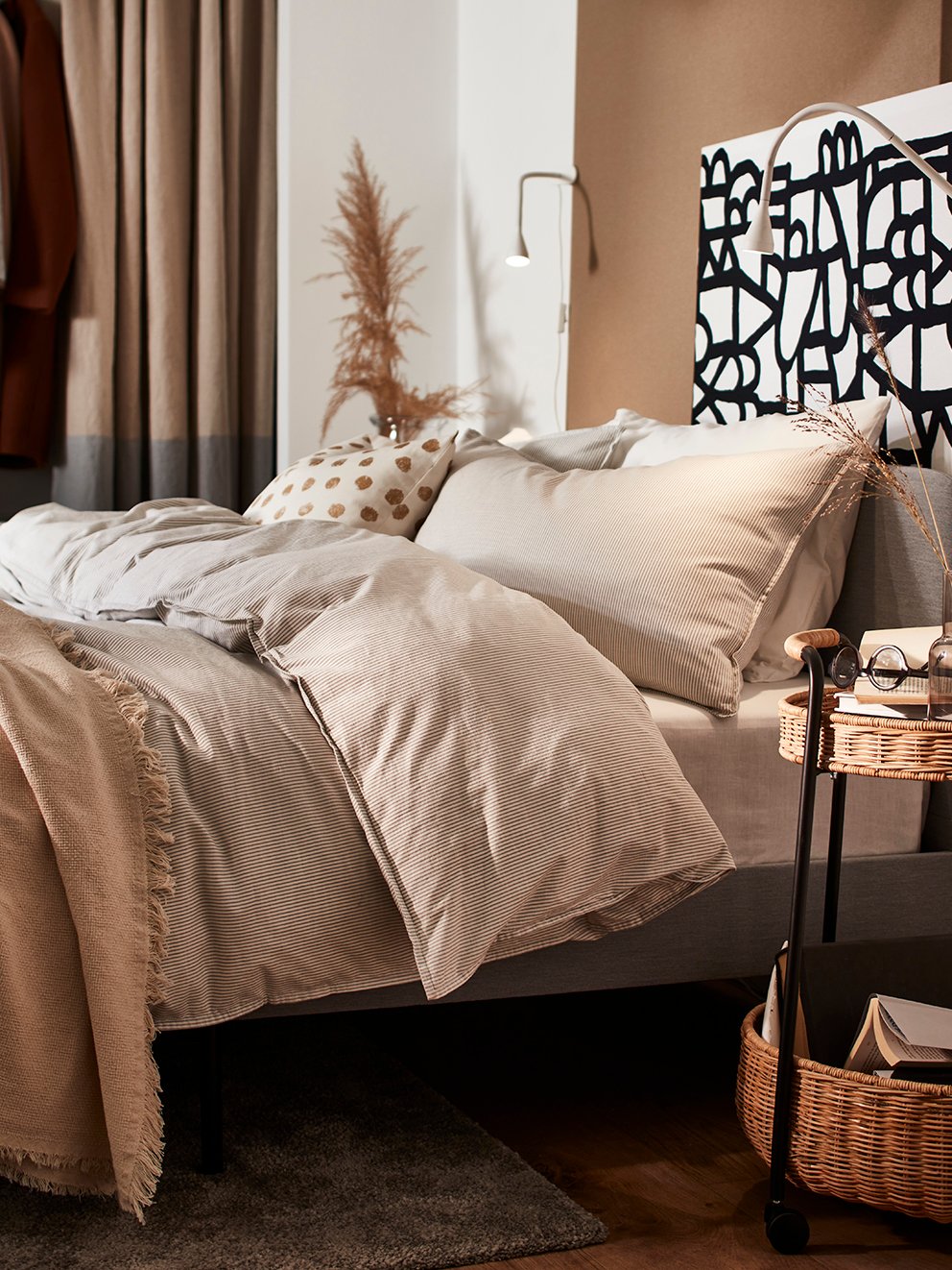 A LUBBAN trolley table stands beside a SLATTUM upholstered bed with bedding including BERGPALM bed linen.