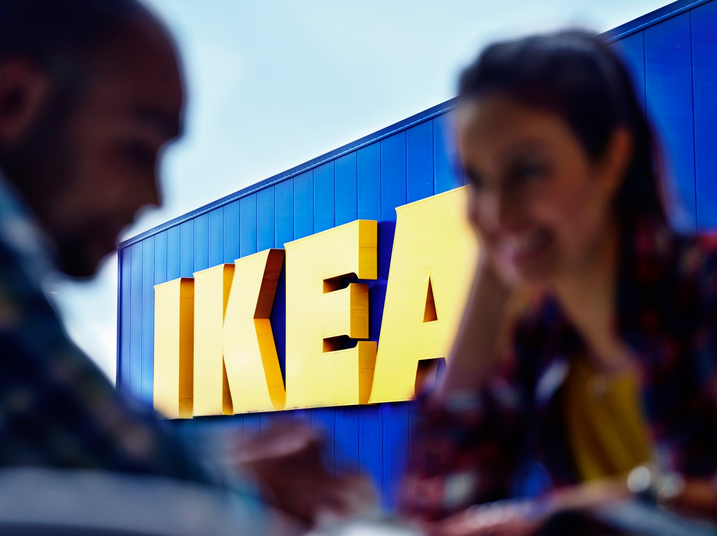 Two people silhouetted against the IKEA logo on an IKEA store.