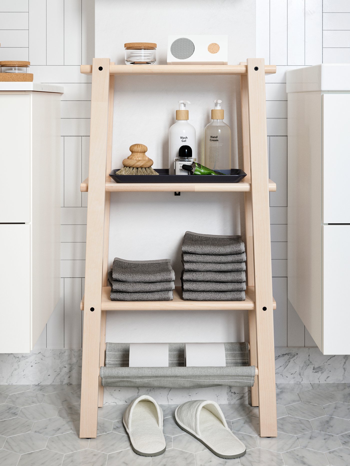 Estantería VILTO de abedul con toallas grises perfectamente dobladas, altavoz Bluetooth y productos de belleza en las estanterías.