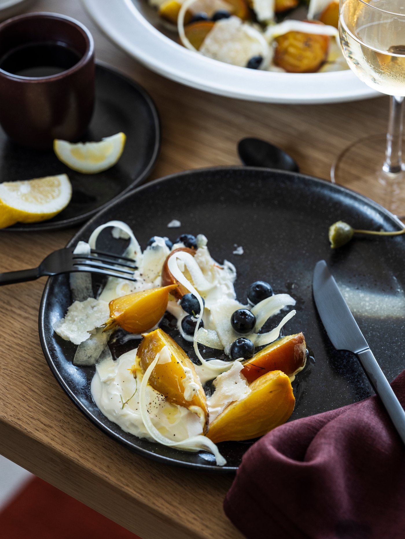 Une assiette noire remplie de nourriture avec un couteau noir posé dessus