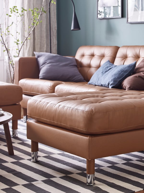 A LANDSKRONA gold brown leather sofa and chaise longue in a living room with a lamp and pictures on the wall.