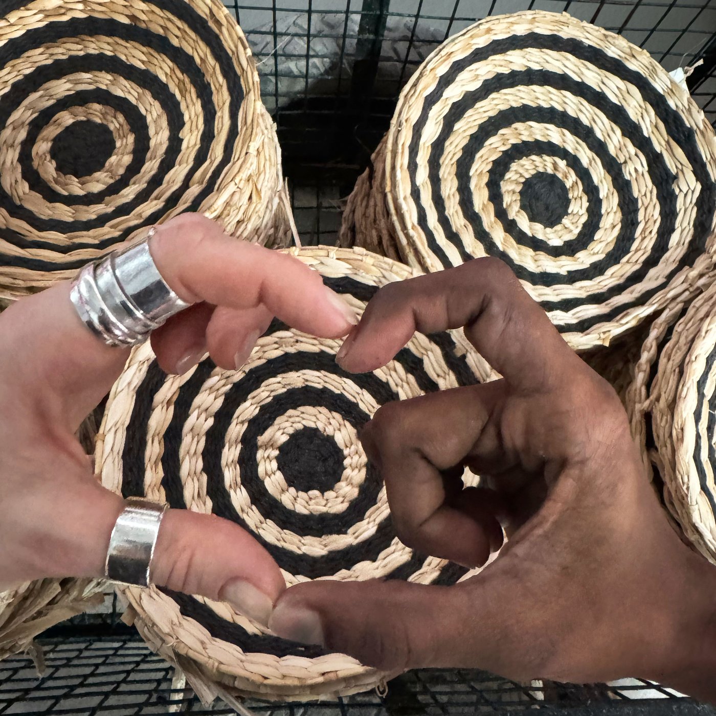 Two hands of people with different skin colours form a heart in front of piles of MÄVINN wall decoration.