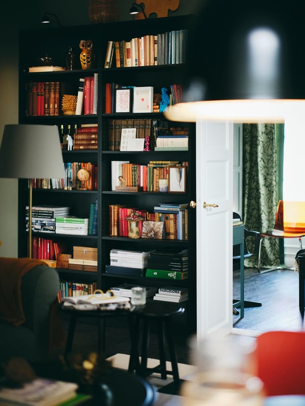 A living area with a set of 2 black KRAGSTA nest of tables in front of two black-brown BILLY bookcases filled with books.