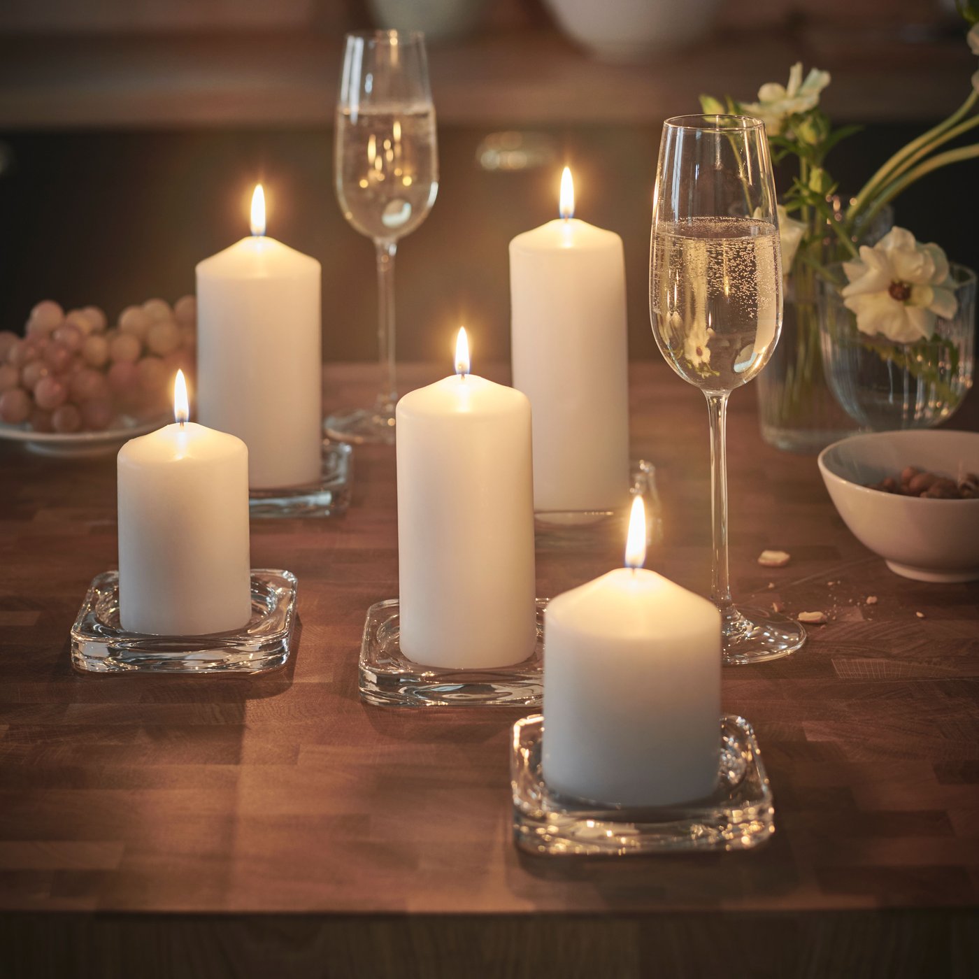 To champagneglas står på et bord fyldt med sterinlys.