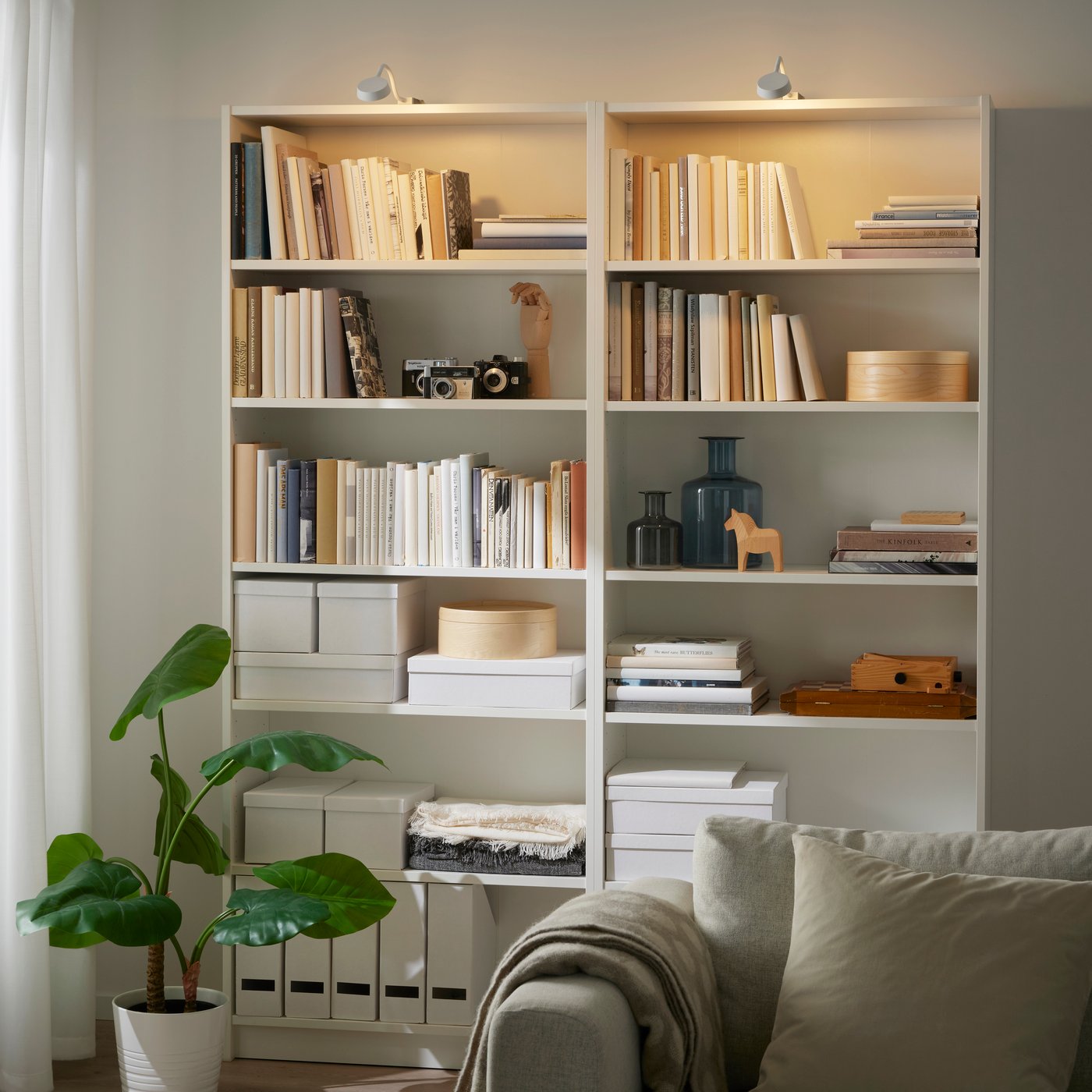 A white bookshelf in the living room with two YTBERG bookshelf lights above it.