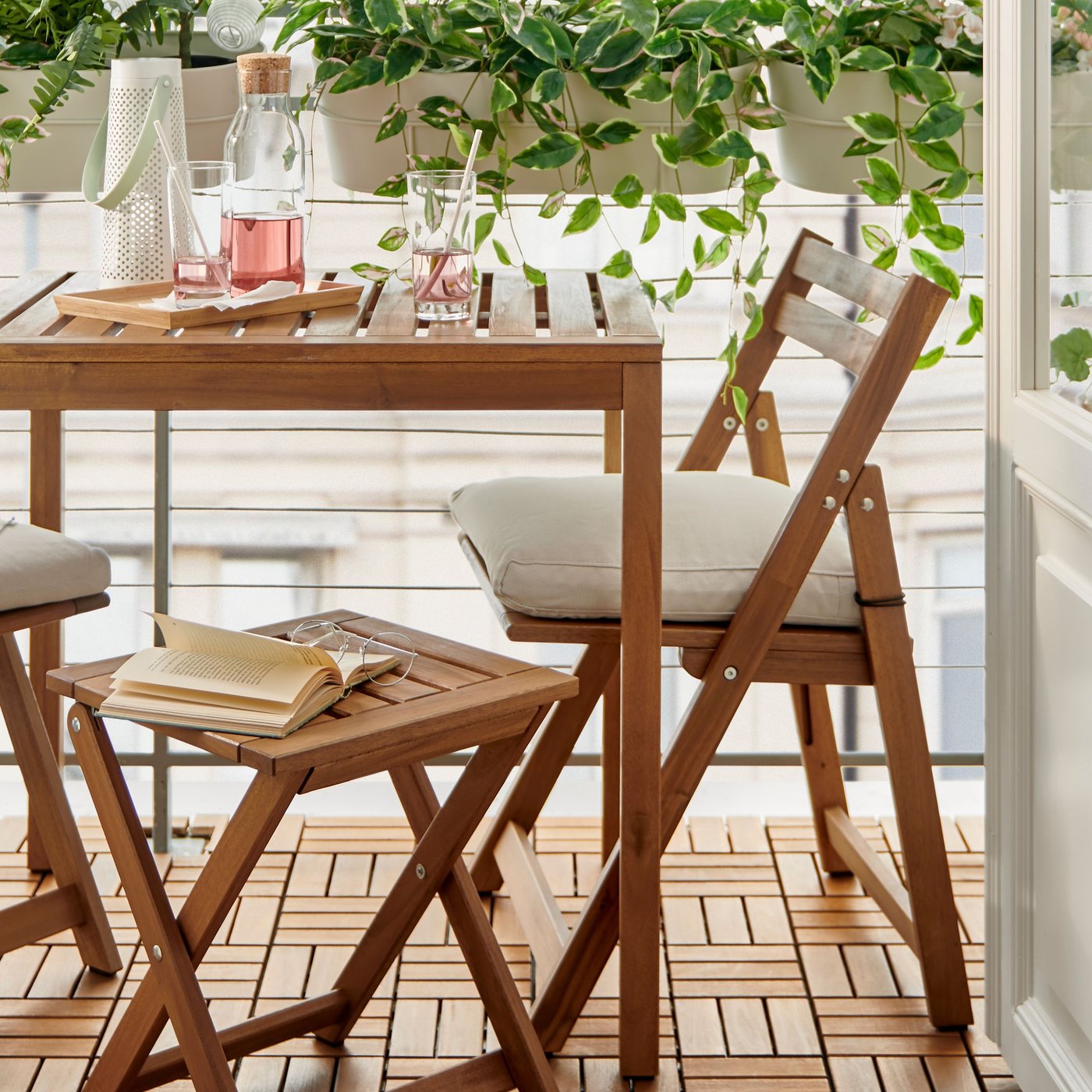 Una mesa de terraza de madera en un balcón con vasos y jarros de vidrio en su superficie.
