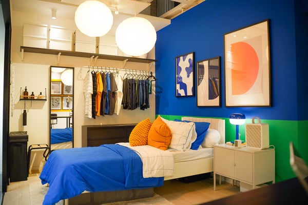 A black-brown KULLEN chest of 6 drawers, a white BRUKSVARA bed frae in a room setting in IKEA Tampines