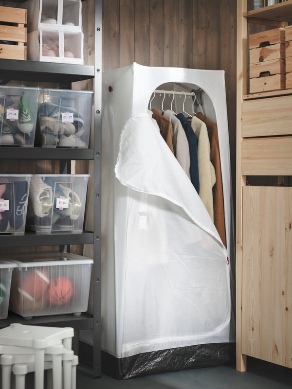 Ein IVAR-Schrank aus Kiefernholz in einem Keller mit einem VUKU Kleiderschrank dazwischen. 