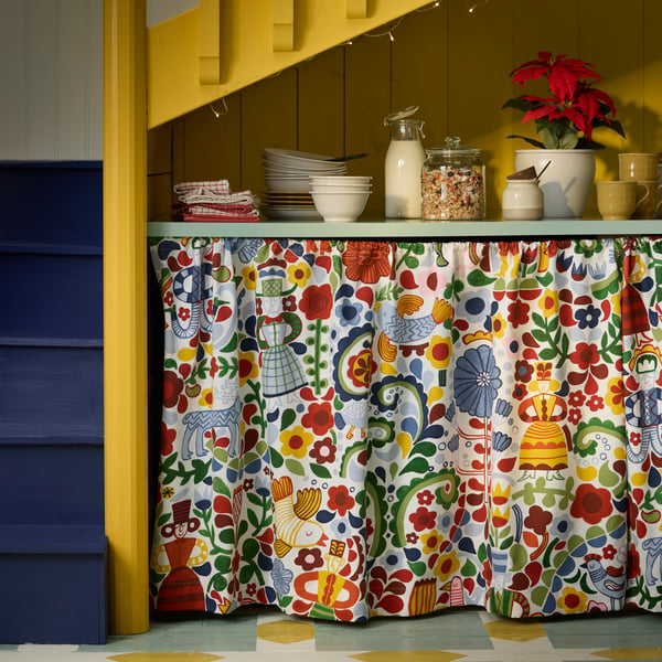 A patterned, multicolour curtain made with CINTIAKAKTUS pre-cut fabric is placed under a kitchen counter.