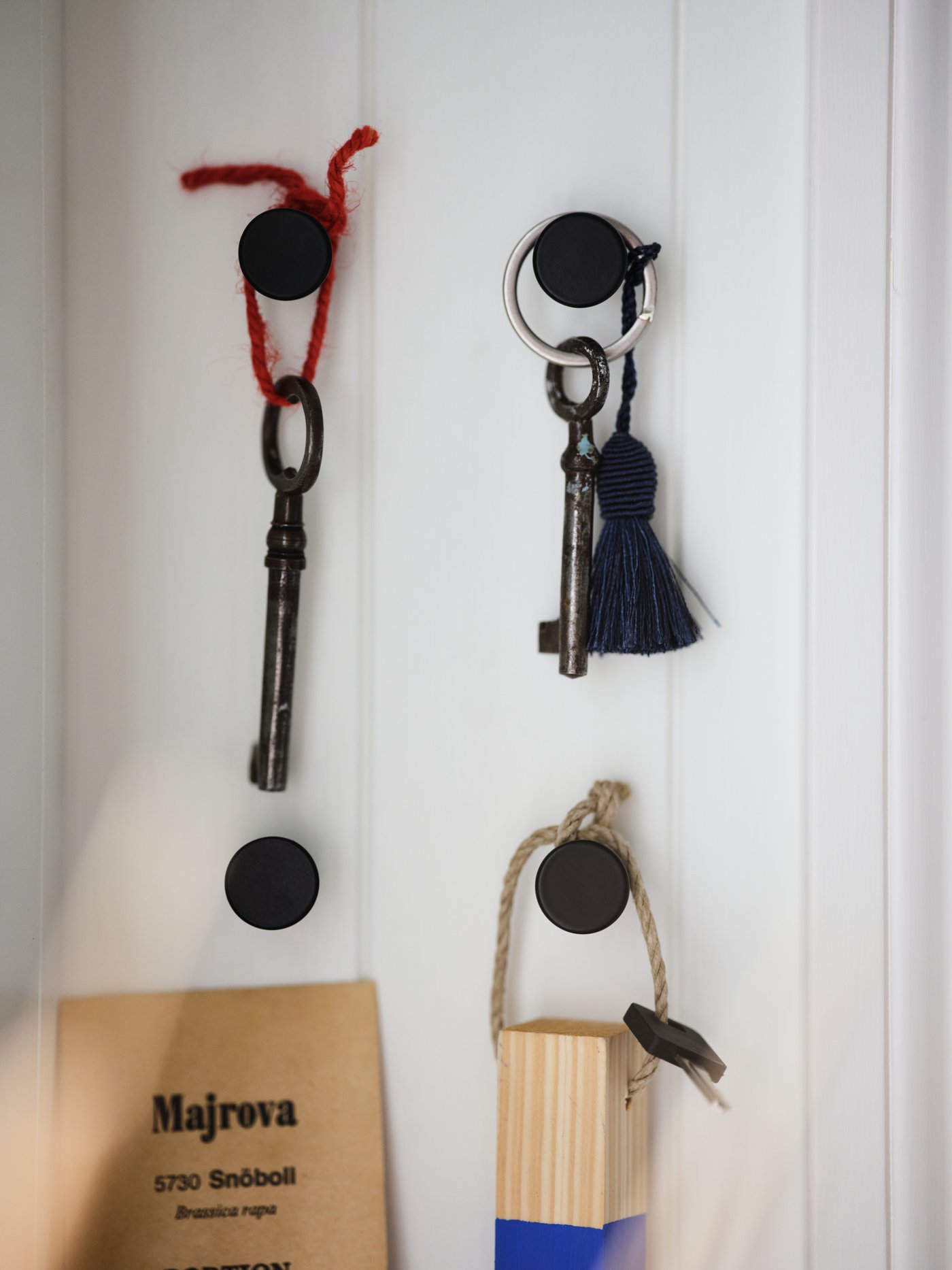 Clés et accessoires sur 4 crochets SKOGSVIKEN noirs, installés de façon à former un rectangle, sur une cloison blanche.