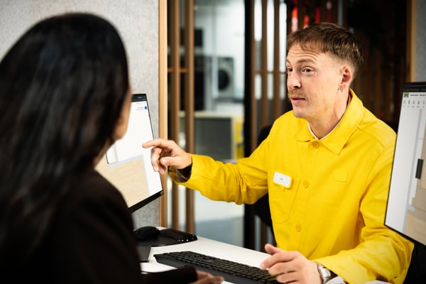 An IKEA staff member is showing a design to a customer