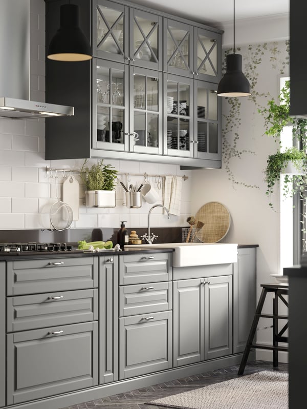 A kitchen with BODBYN grey fronts and glass doors, a HAVSEN white ceramic sink and black worktop.