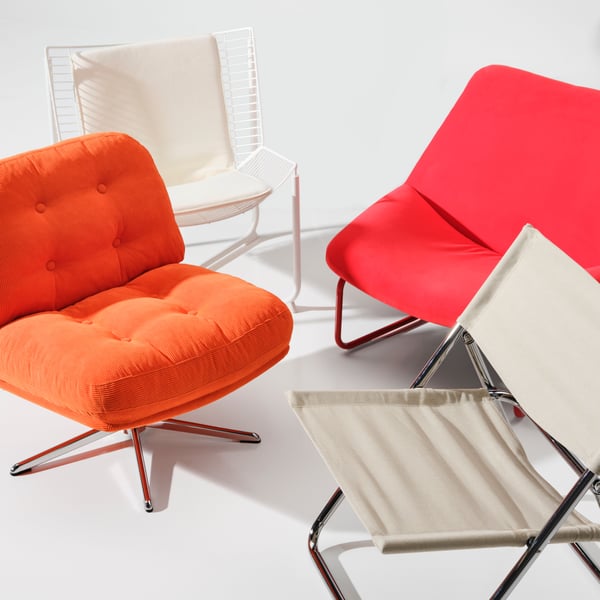 Four different chairs from the Nytillverkad collection are placed in a white room. Among them is a DYVLINGE swivel armchair.
