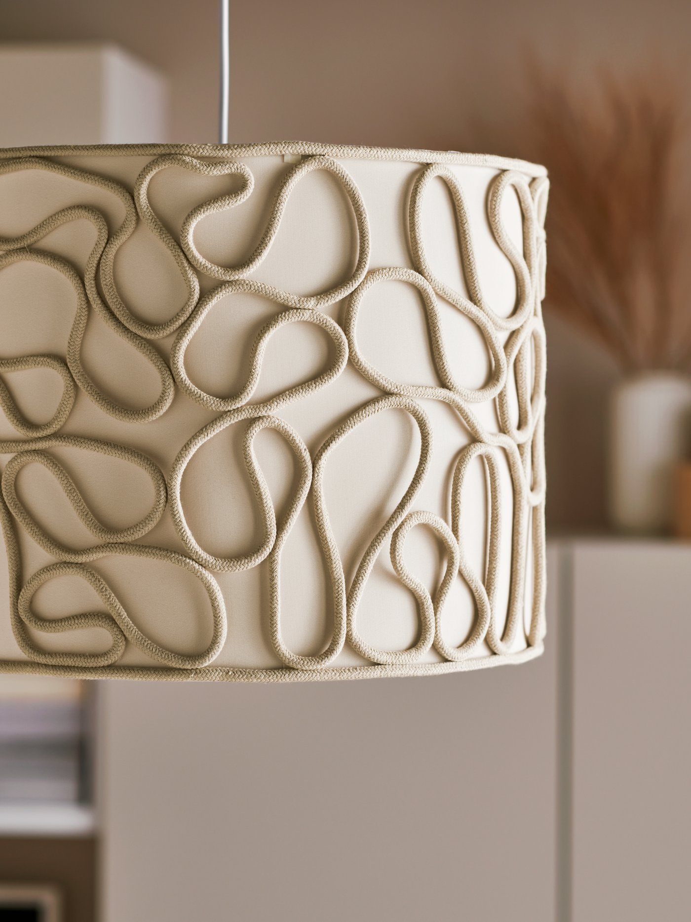 The rope detailing that winds over a textile-covered inside of a white VINGMAST pendant lamp.