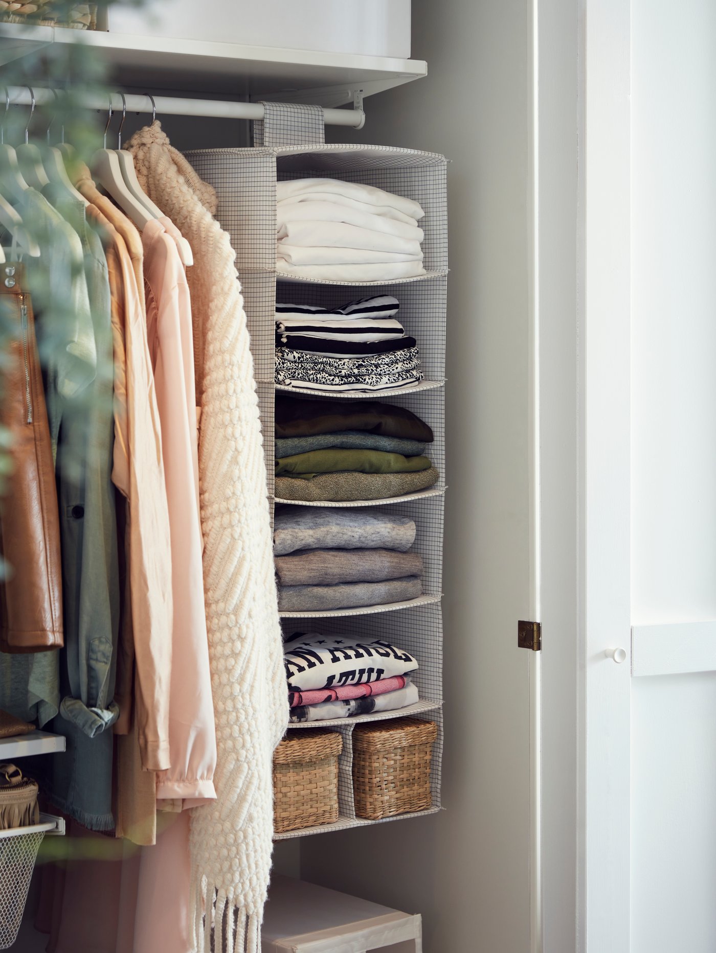 Some clothes and a white/grey STUK storage with 7 compartments hang from a rail in a white BOAXEL wardrobe combination.