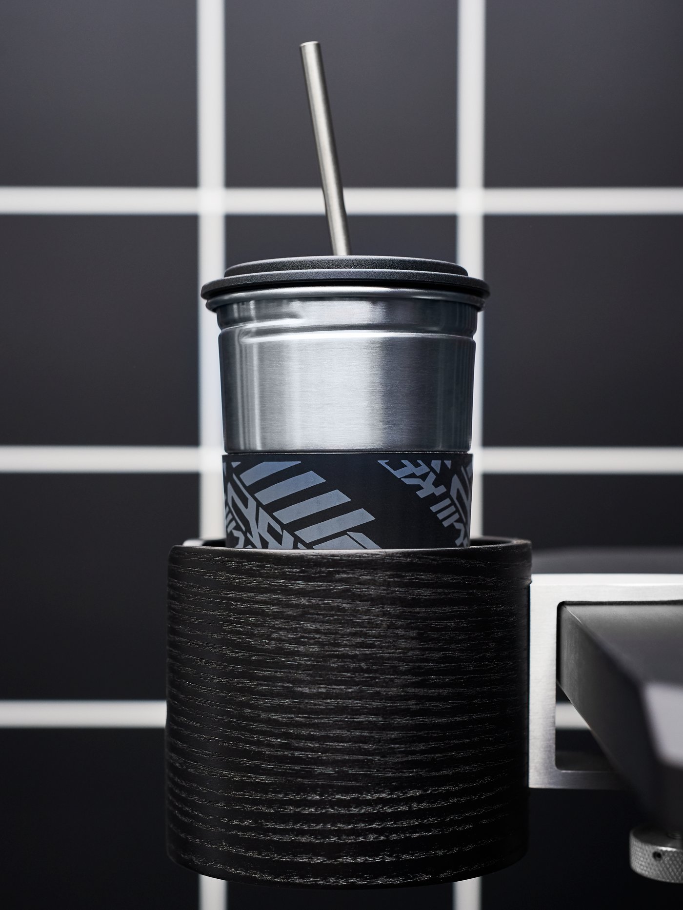 Soporte para vasos negro LÅNESPELARE con un vaso metálico LÅNESPELARE