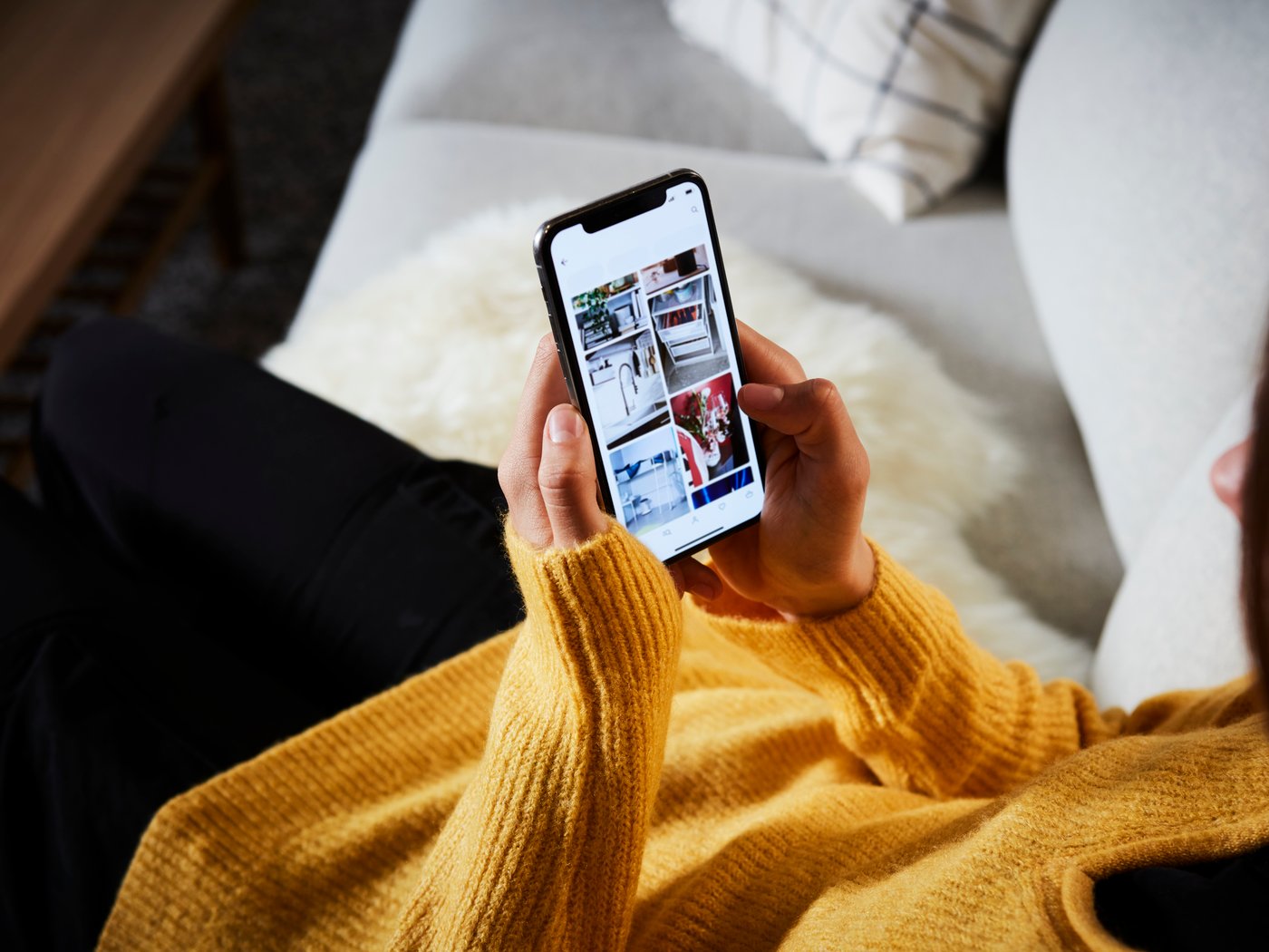 A woman wearing a yellow jumper using a mobile phone.