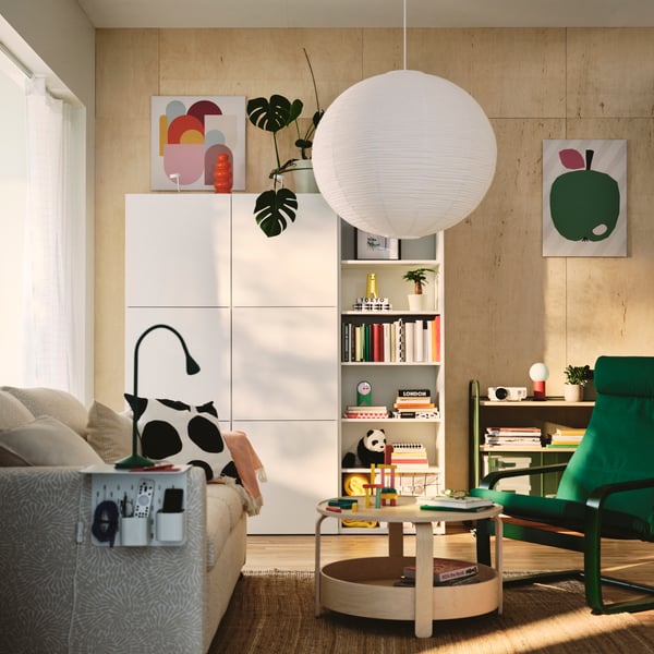 Wohnzimmer mit einem weißen BESTÅ Schrank. Daneben steht ein weißes BESTÅ Regal.