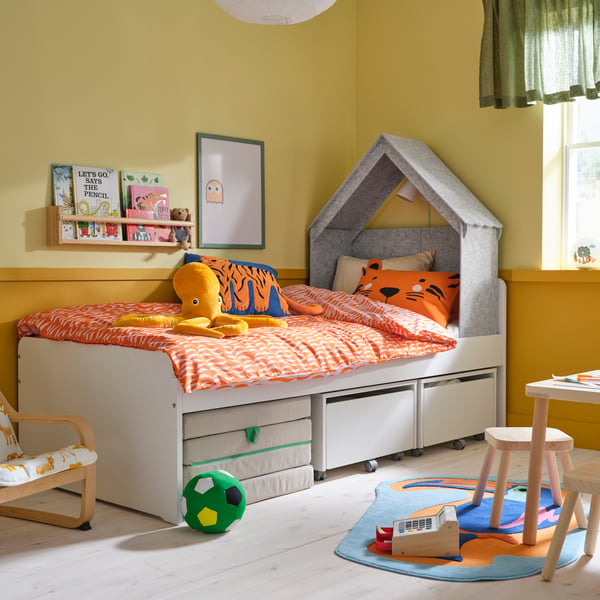 Ein SLÄKT Bett steht in einem Kinderzimmer, darüber ist ein Baldachin in Häuschen-Form