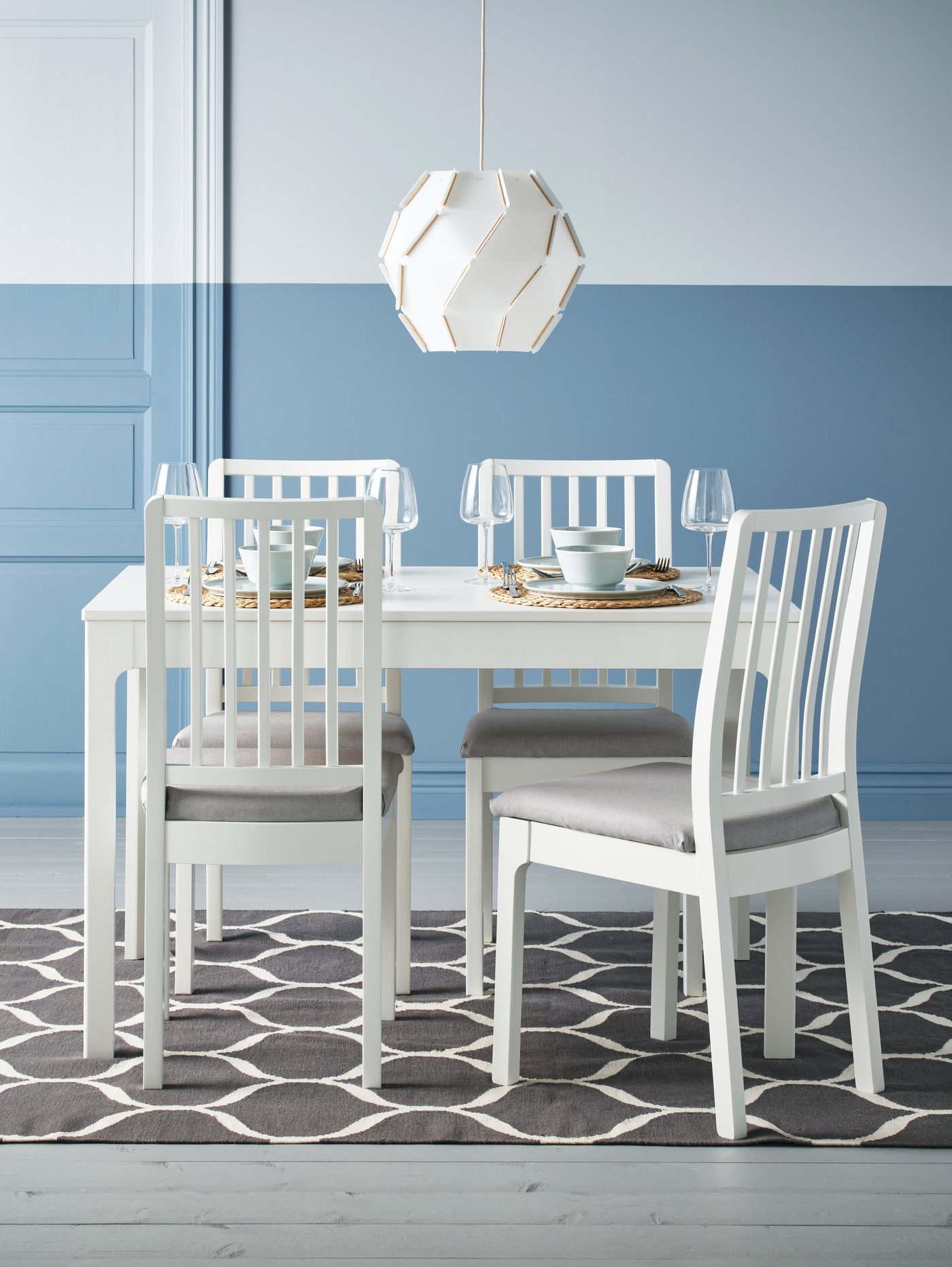Un comedor blanco con 4 sillas con asiento tapizado.
