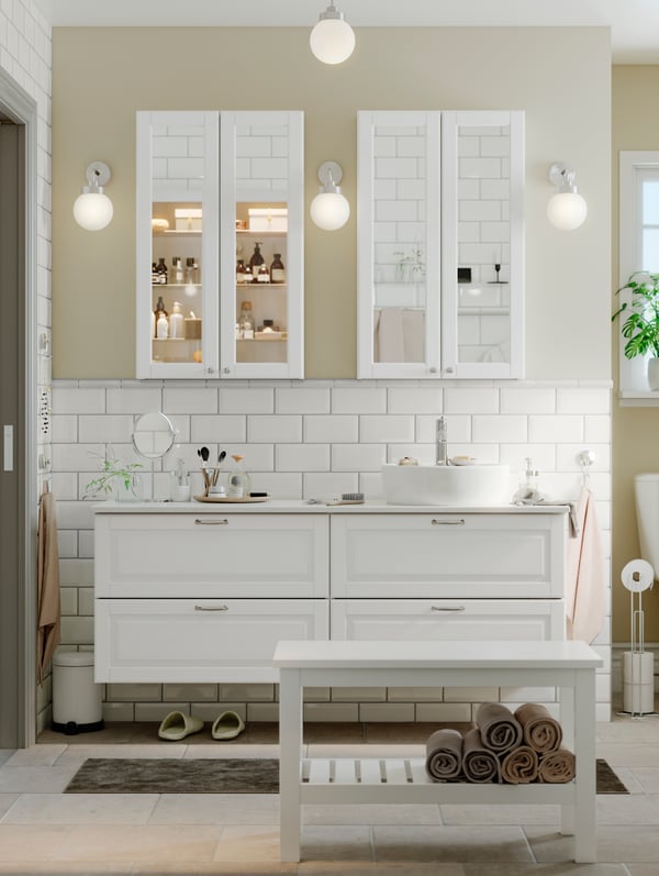 A light-coloured bathroom with two wash-stands side by side and two GODMORGON mirror cabinets and three lamps on the wall.