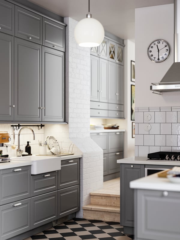 A kitchen with grey BODBYN fronts and a white HAVSEN sink bowl with visible front leading into a hallway with more cabinets.