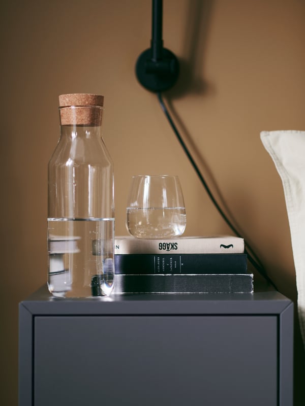 Vaso de vidrio DYRGRIP sobre 3 libros y junto a botella con agua IKEA 365+.