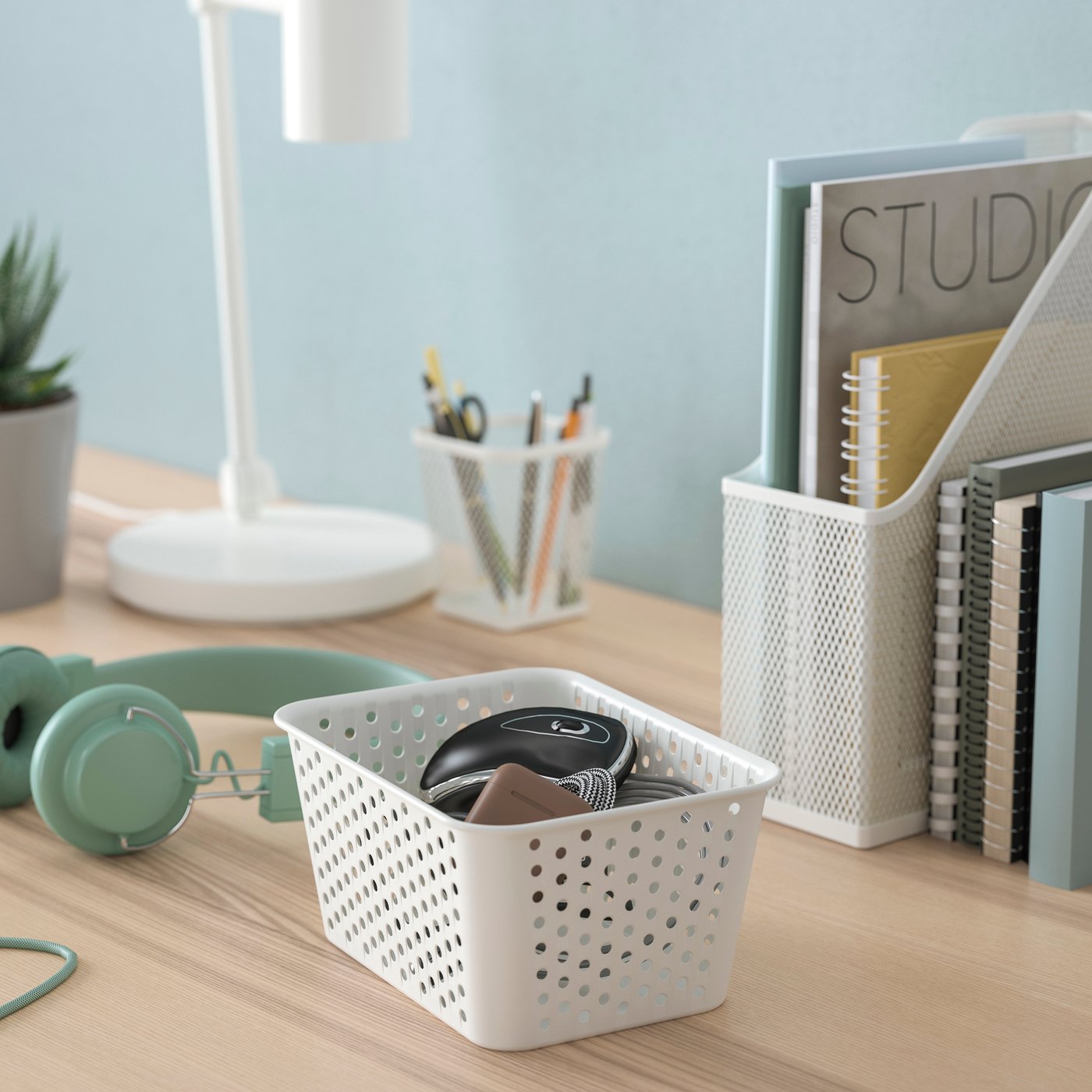 Una canasto de plástico blanco PLOGSVÄNG sobre una mesa con artículos de entrenamiento adentro.