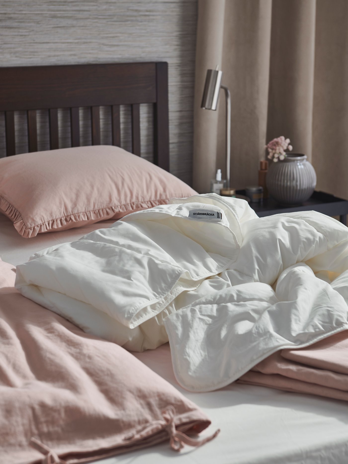A bedroom and IDANÄS bed get prepped for a linen change for spring with STJÄRNBRÄCKA duvet and KRANSKRAGE duvet sets.