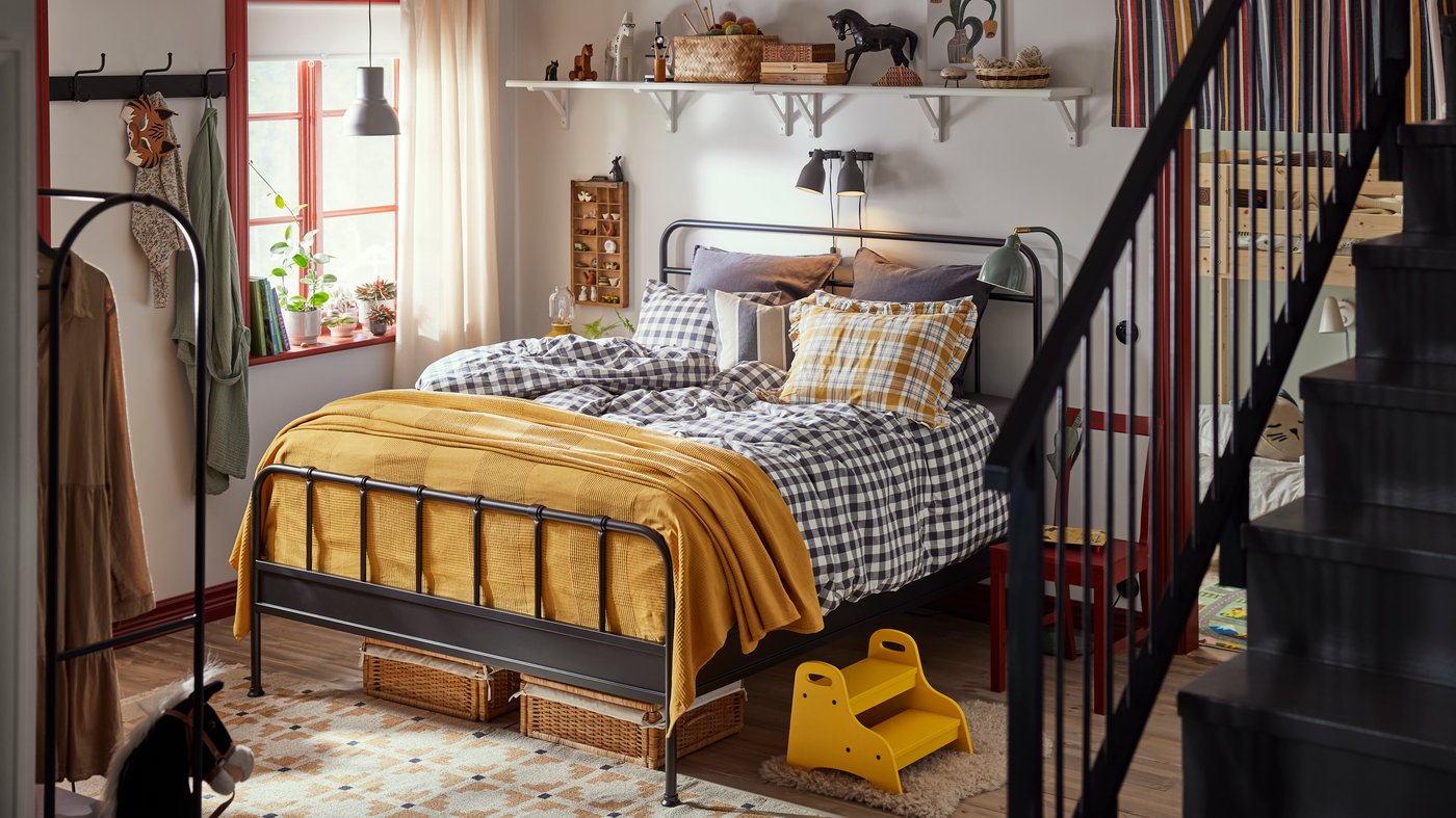 Family bedroom with STJÄRNÖ classic bedframe in anthracite with checkered sheets. Blanket and details in bright yellow.