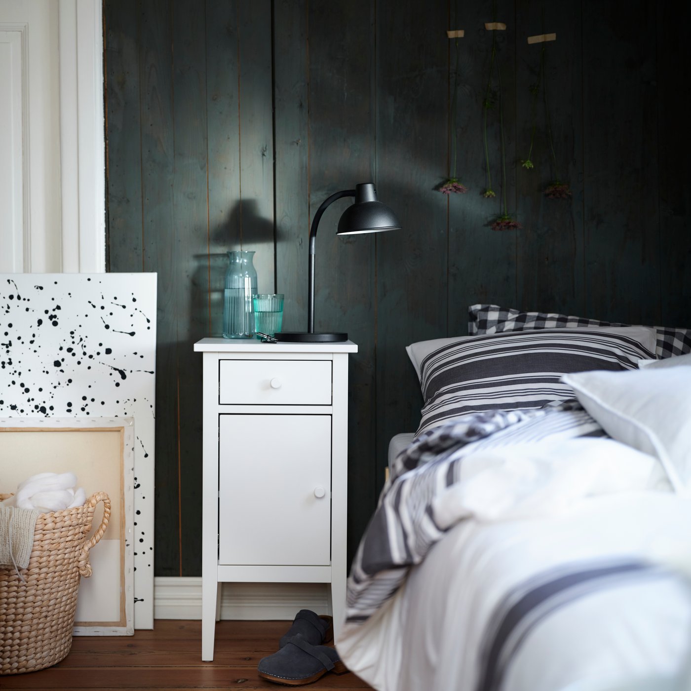 GULLABERG bedside table in white placed beside a bed with striped bedding in a dark-panelled bedroom.