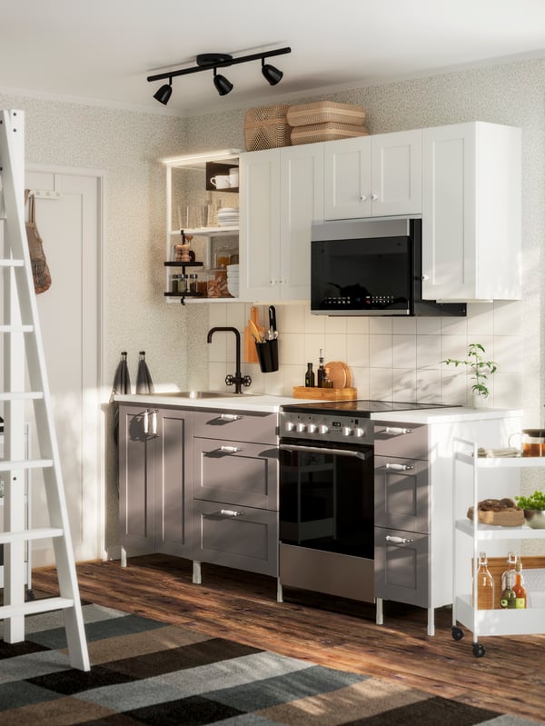 Una cocina de estilo tradicional con suelos de madera y cajas, y una cocina ENHET con frentes blancos y grises.