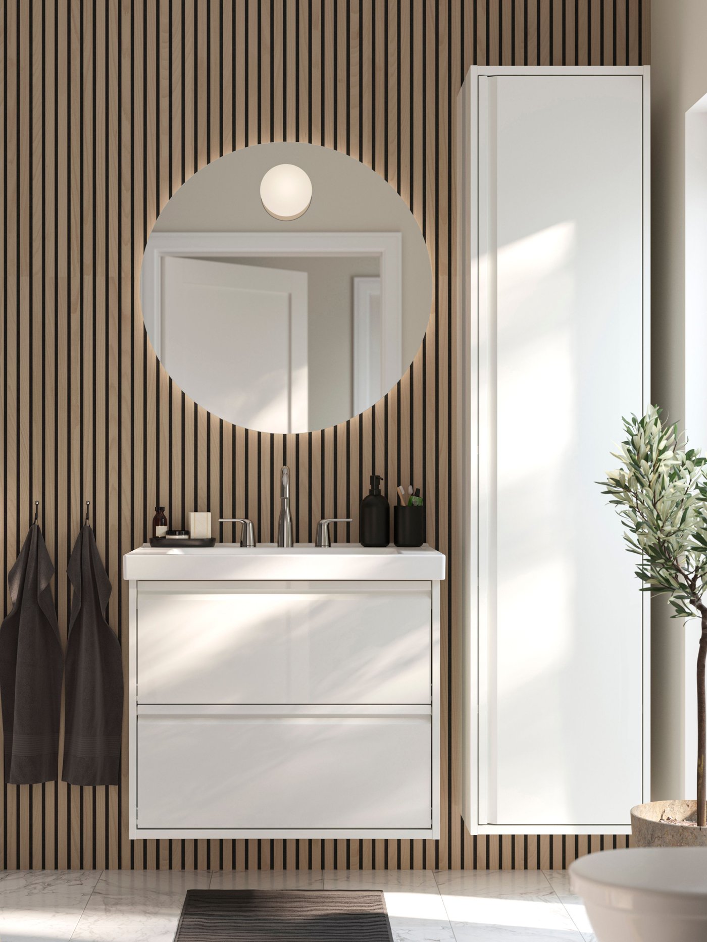 A high-gloss white ÄNGSJÖN high cabinet with door in the bathroom