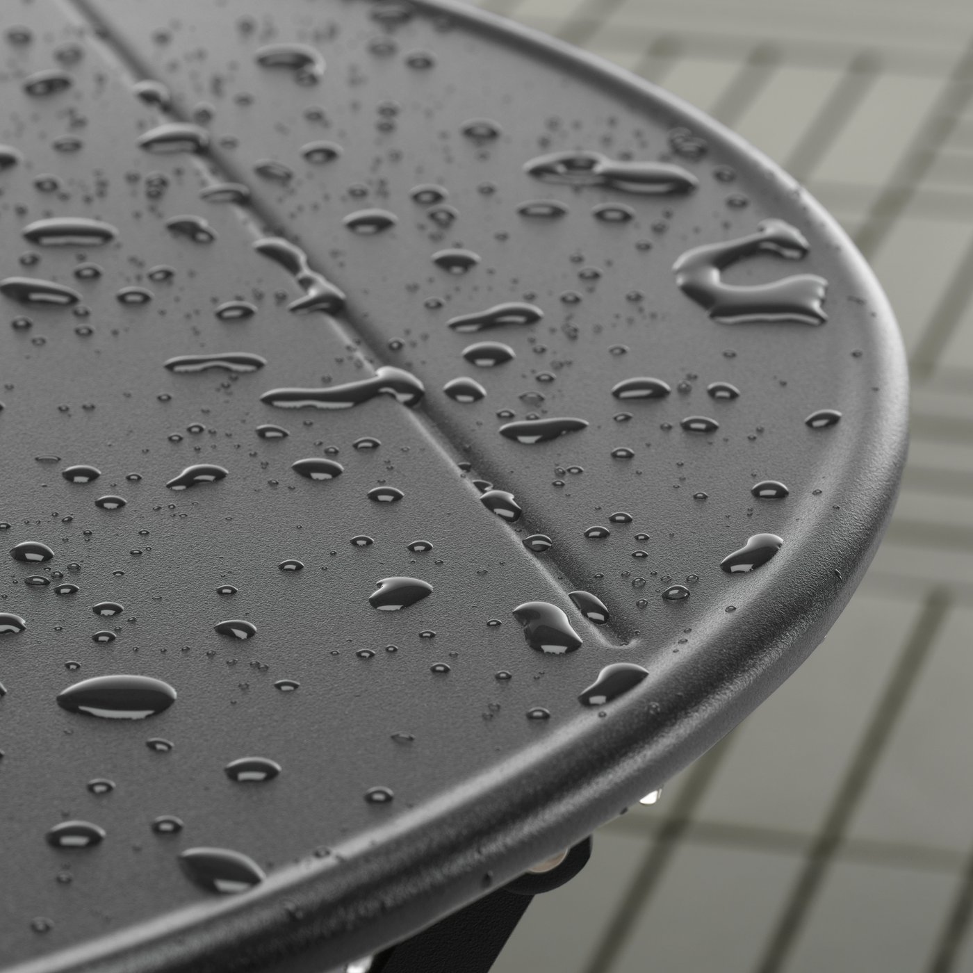 A close-up of raindrops on an anthracite SUNDSÖ outdoor table made from powder-coated steel.