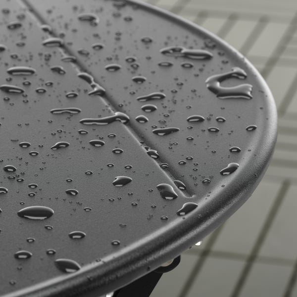 Gros plan sur des gouttes de pluie sur une table d’extérieur SUNDSÖ anthracite en acier peint époxy.